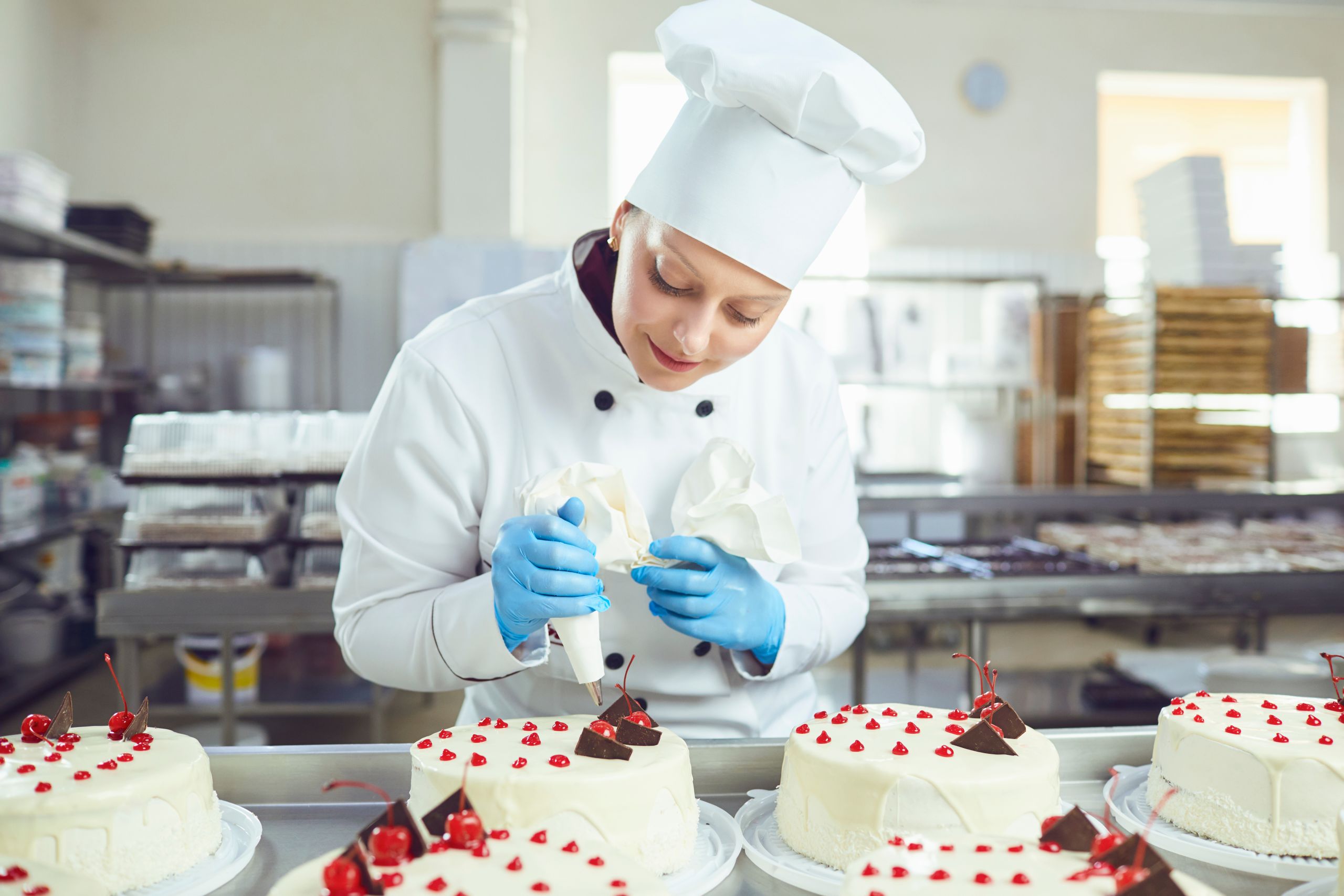 Woman confectioner with pastry cake in his hand smiling at the bakery.