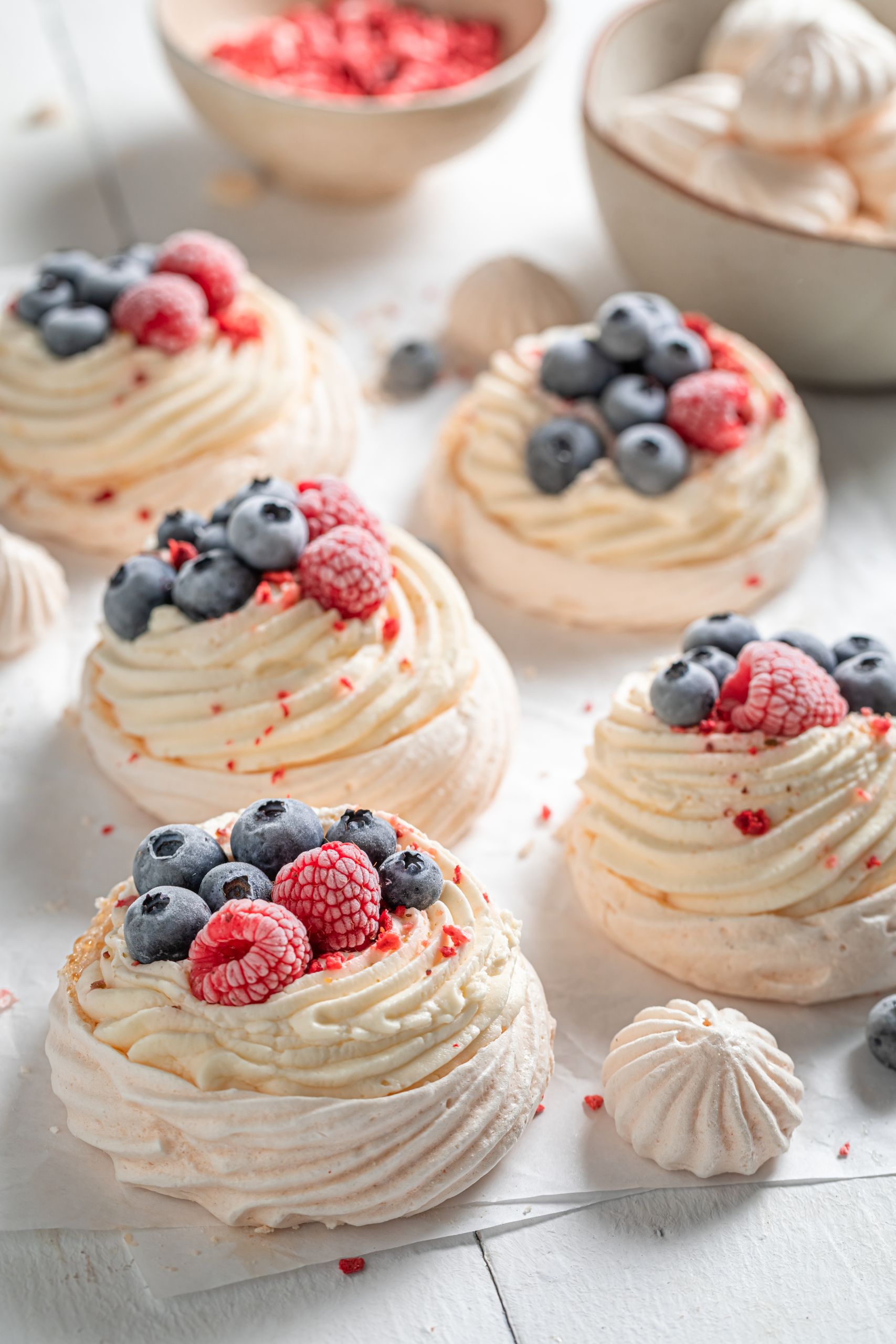 Delicious mini Pavlova cake with frozen fruits and meringue on white baking paper