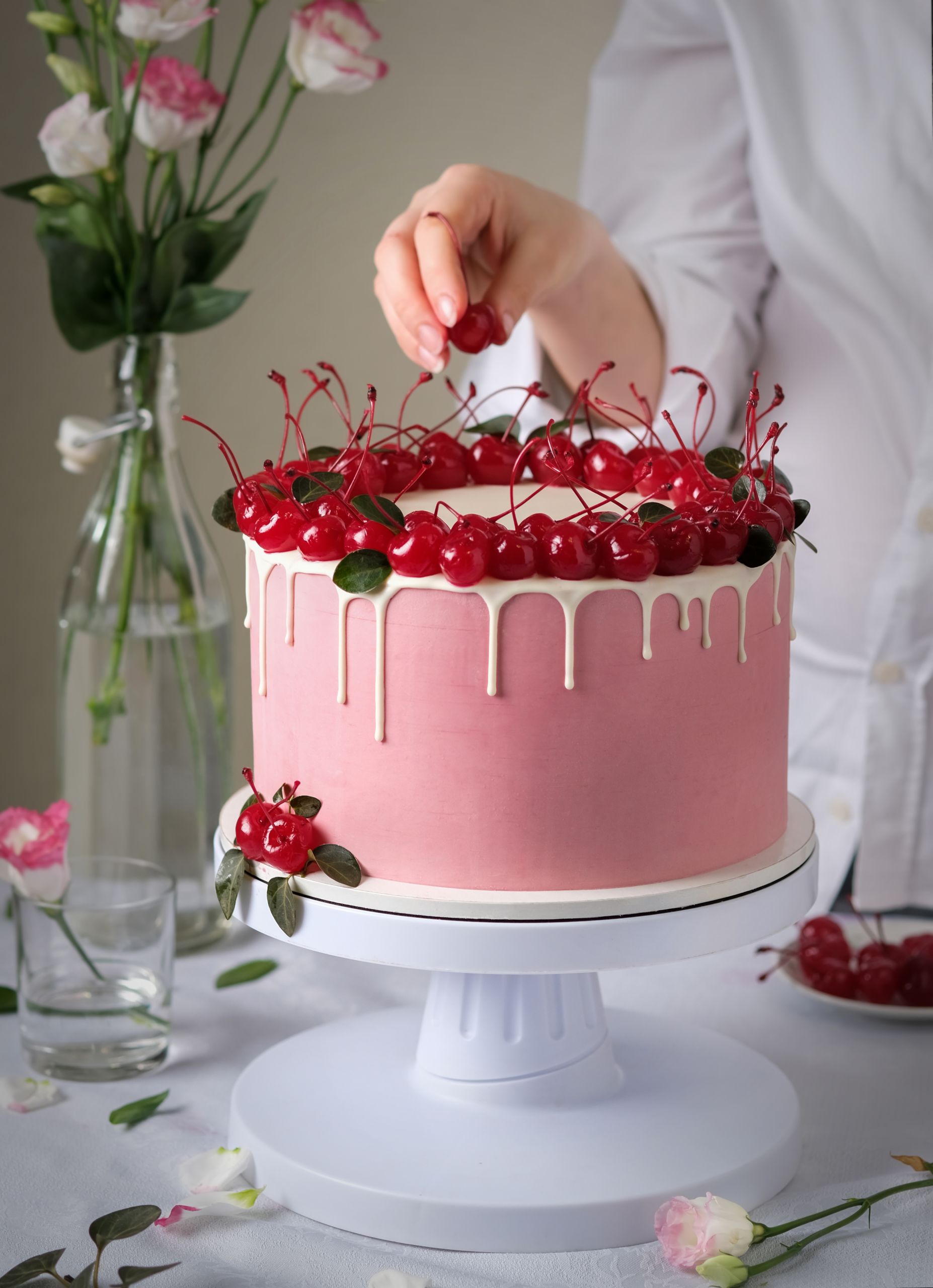 Cake with cherry. The confectioner decorates the cake